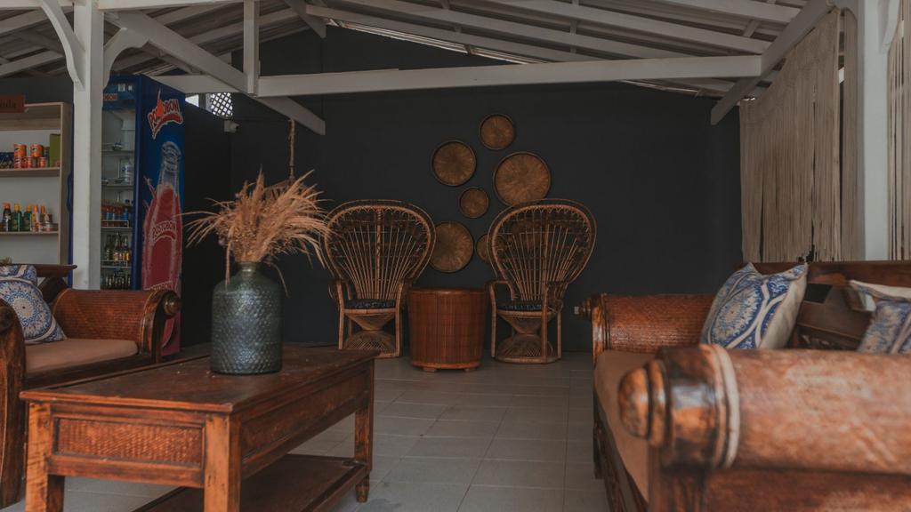 Lobby acogedor sillas de mimbre, cojines estampados y área de refrigerios con bebidas y snacks